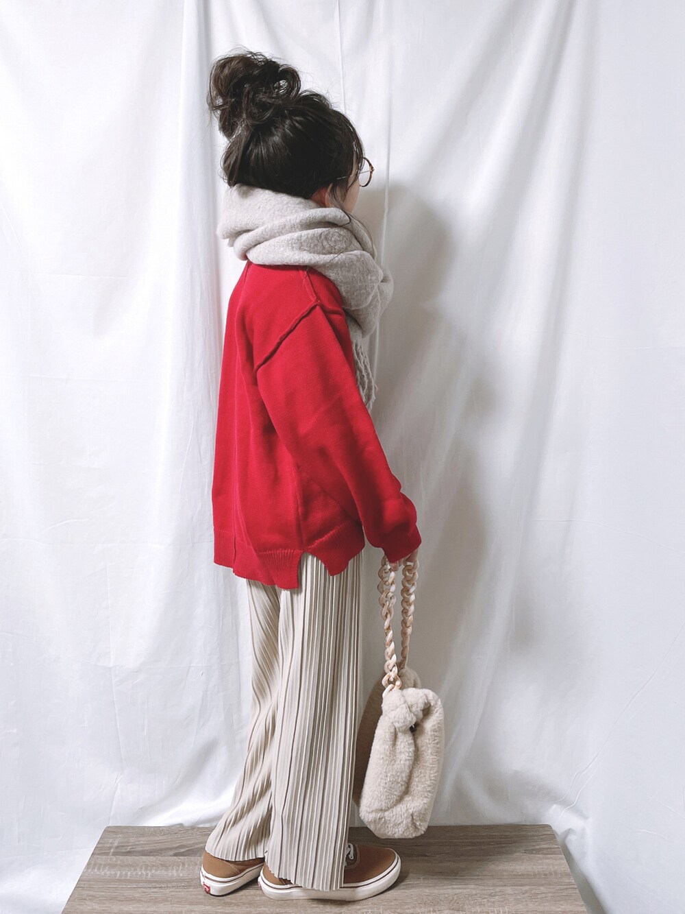 レッド系のニット/セーター、ベージュ系のその他パンツ、ホワイト系のバッグを着用したキッズの冬コーディネートの4枚目の写真
