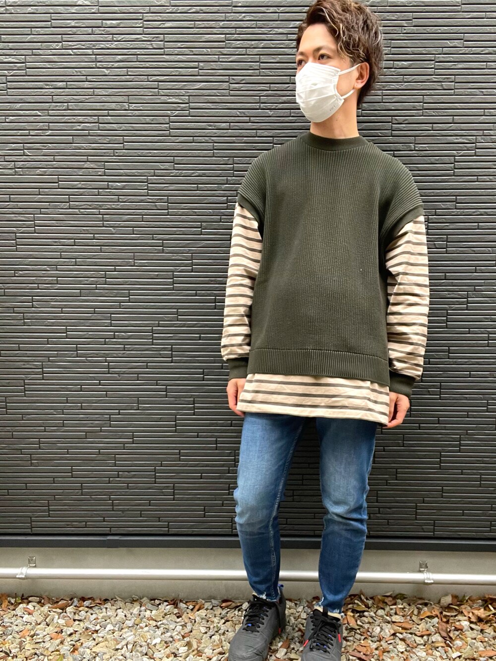 ベージュ系のブルゾン、グリーン系のニット/セーター、ブルー系のデニムパンツを着用したメンズの冬コーディネートの2枚目の写真