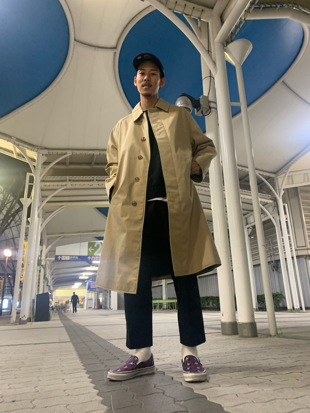 ブラック系のスラックス、ブラック系のニット/セーター、ベージュ系のトレンチコートを着用したメンズの秋コーディネートの2枚目の写真