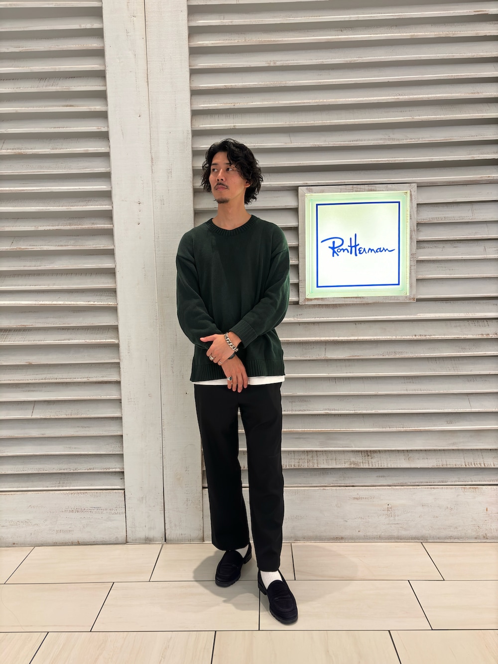ブラック系のローファー、ブラック系のスラックス、グリーン系のニット/セーターを着用したメンズの秋コーディネートの2枚目の写真