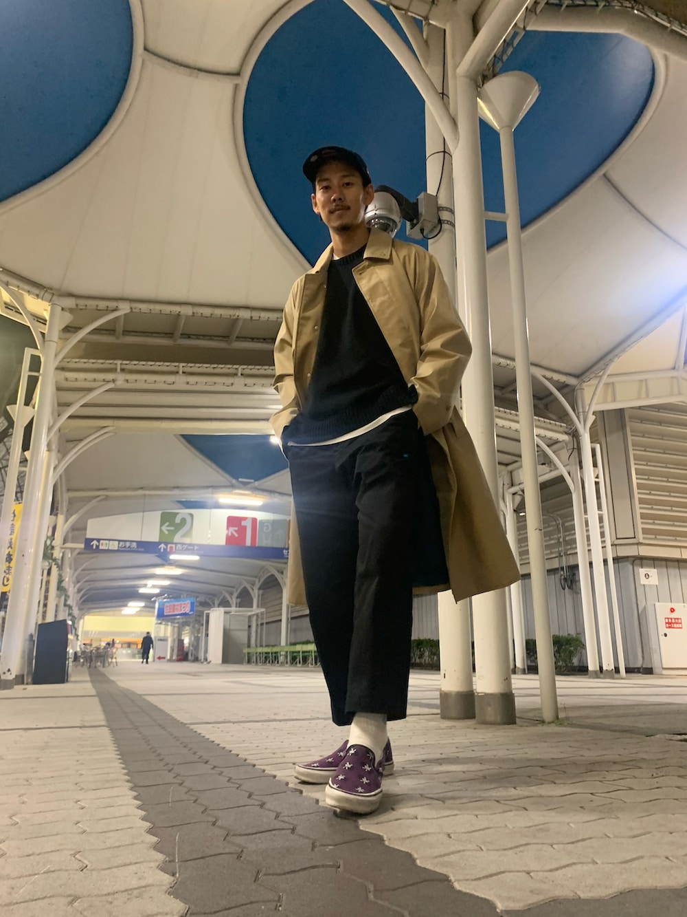 ブラック系のスラックス、ブラック系のニット/セーター、ベージュ系のトレンチコートを着用したメンズの秋コーディネートの4枚目の写真