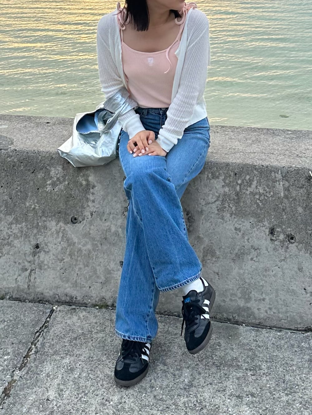 ピンク系のキャミソール、ブルー系のデニムパンツ、ホワイト系のカーディガン/ボレロを着用したレディースの春コーディネートの2枚目の写真