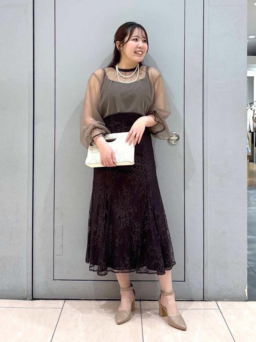 ベージュ系のショルダーバッグ、ベージュ系のパンプス、グレー系のドレスを着用したレディースの春コーディネートの4枚目の写真