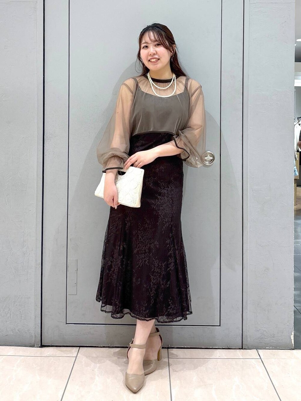 ベージュ系のショルダーバッグ、ベージュ系のパンプス、グレー系のドレスを着用したレディースの春コーディネートの3枚目の写真