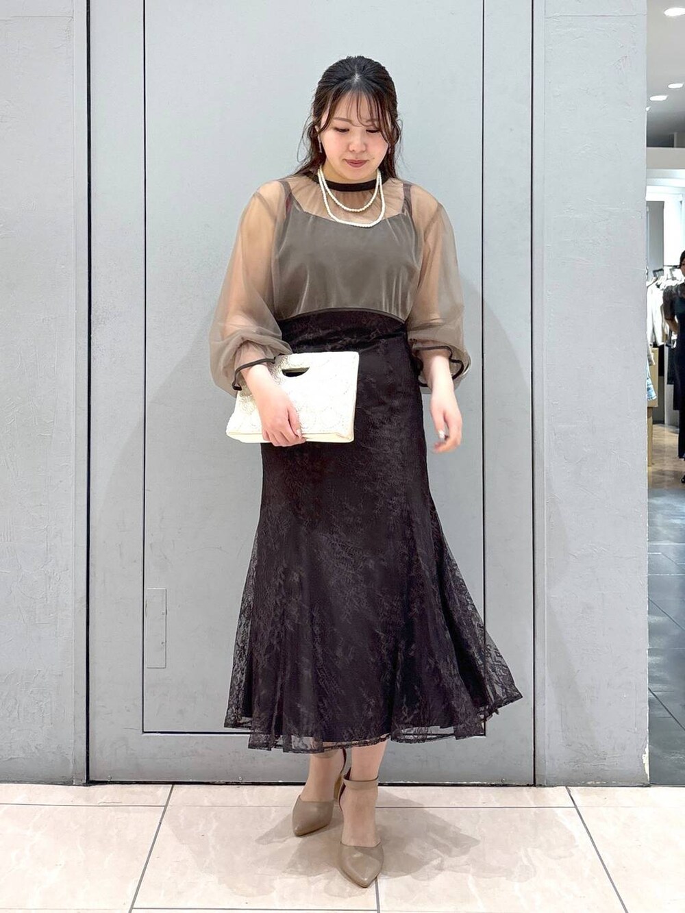 ベージュ系のショルダーバッグ、ベージュ系のパンプス、グレー系のドレスを着用したレディースの春コーディネートの5枚目の写真