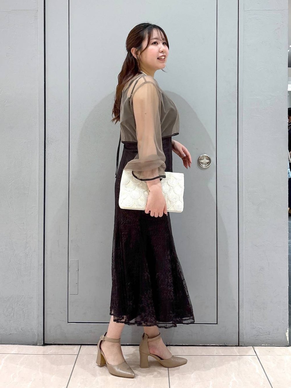 ベージュ系のショルダーバッグ、ベージュ系のパンプス、グレー系のドレスを着用したレディースの春コーディネートの6枚目の写真
