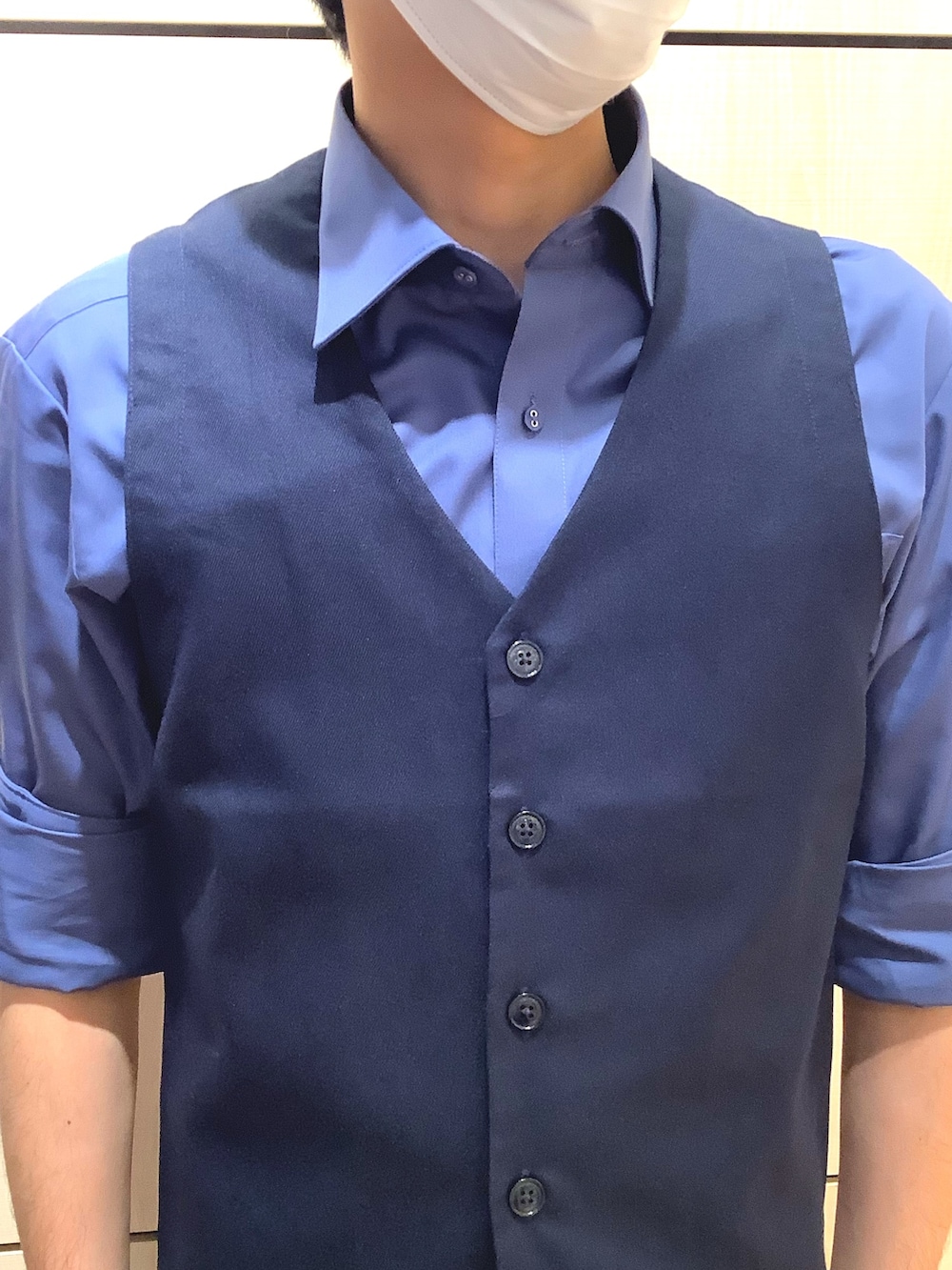 ブルー系のビジネスシャツ、ブルー系のベストを着用したメンズの秋コーディネートの2枚目の写真