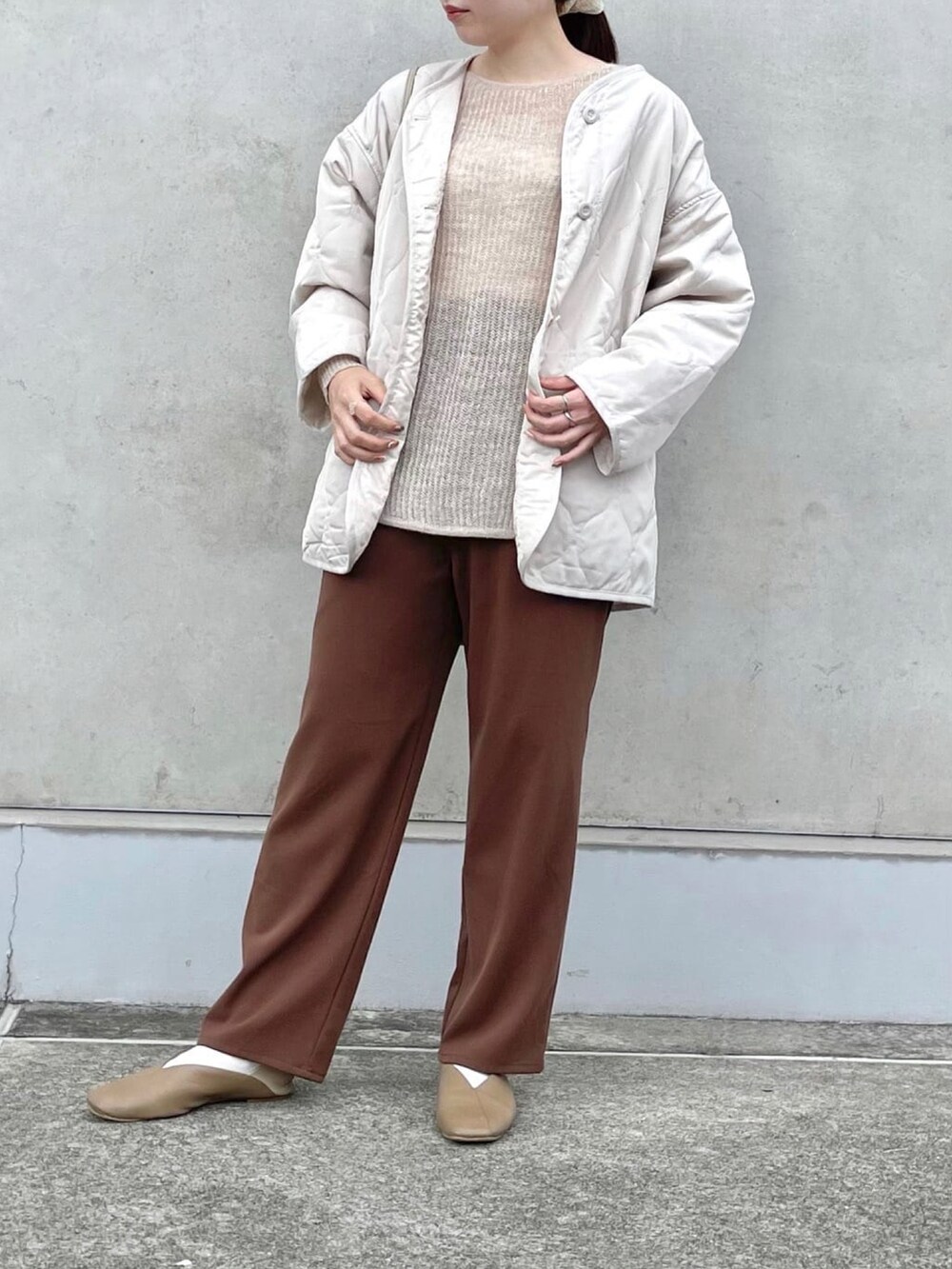 ベージュ系のニット/セーター、ホワイト系のブルゾン、ブラウン系のスラックスを着用したレディースの春コーディネートの2枚目の写真