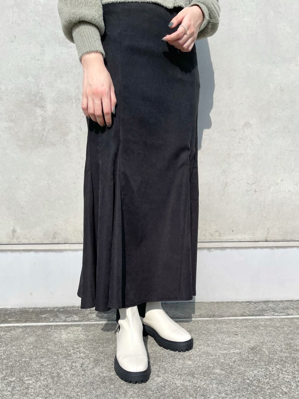 グリーン系のカーディガン/ボレロ、ブラック系のスカート、ブラック系のブーツを着用したレディースの冬コーディネートの3枚目の写真