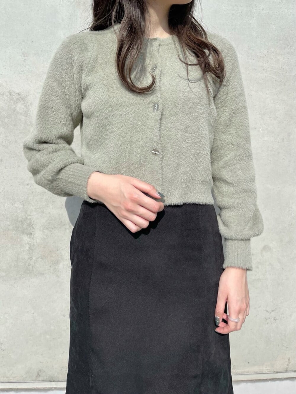 グリーン系のカーディガン/ボレロ、ブラック系のスカート、ブラック系のブーツを着用したレディースの冬コーディネートの2枚目の写真