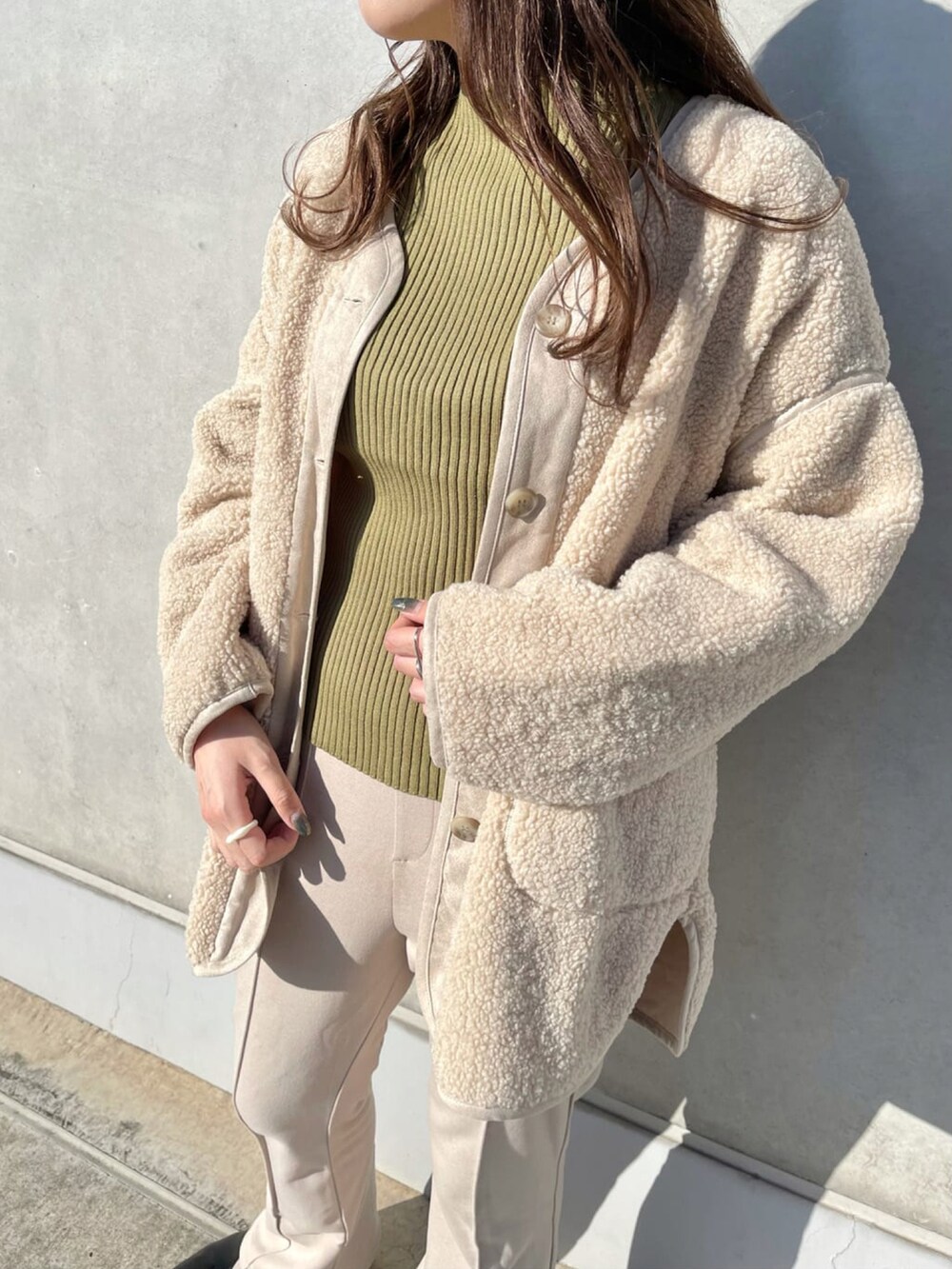 ベージュ系のブルゾン、グリーン系のニット/セーター、ベージュ系のスラックスを着用したレディースの冬コーディネートの3枚目の写真