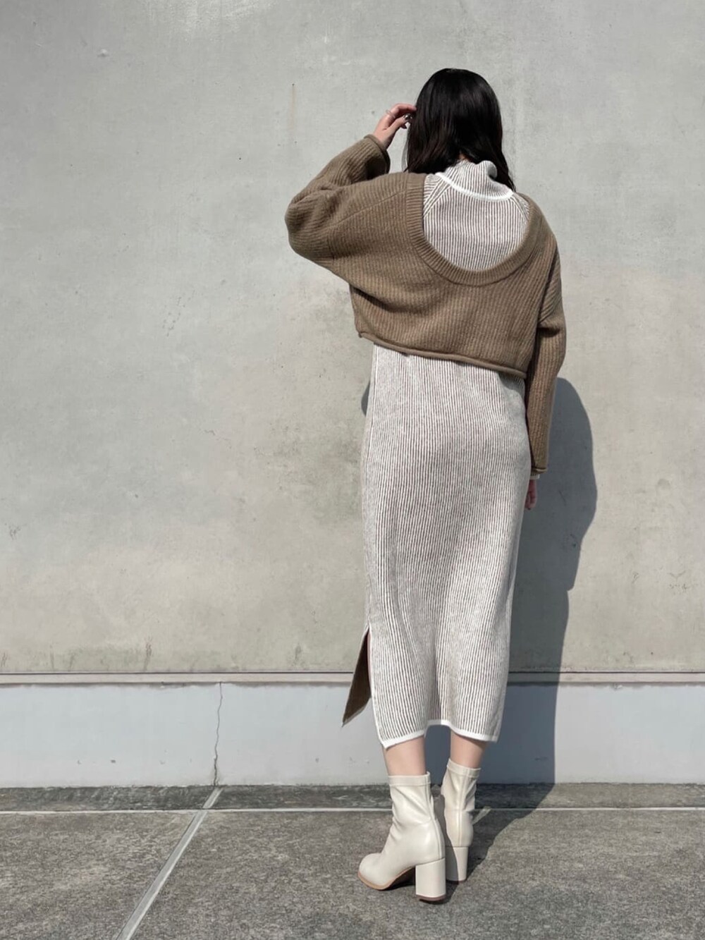 ベージュ系のワンピース、ベージュ系のニット/セーター、ホワイト系のブーツを着用したレディースの冬コーディネートの2枚目の写真