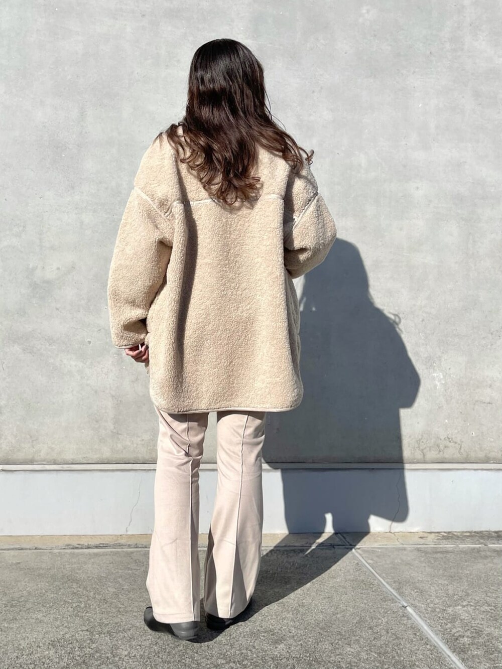 ベージュ系のブルゾン、グリーン系のニット/セーター、ベージュ系のスラックスを着用したレディースの冬コーディネートの2枚目の写真