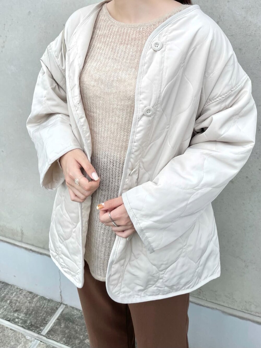 ベージュ系のニット/セーター、ホワイト系のブルゾン、ブラウン系のスラックスを着用したレディースの春コーディネートの3枚目の写真