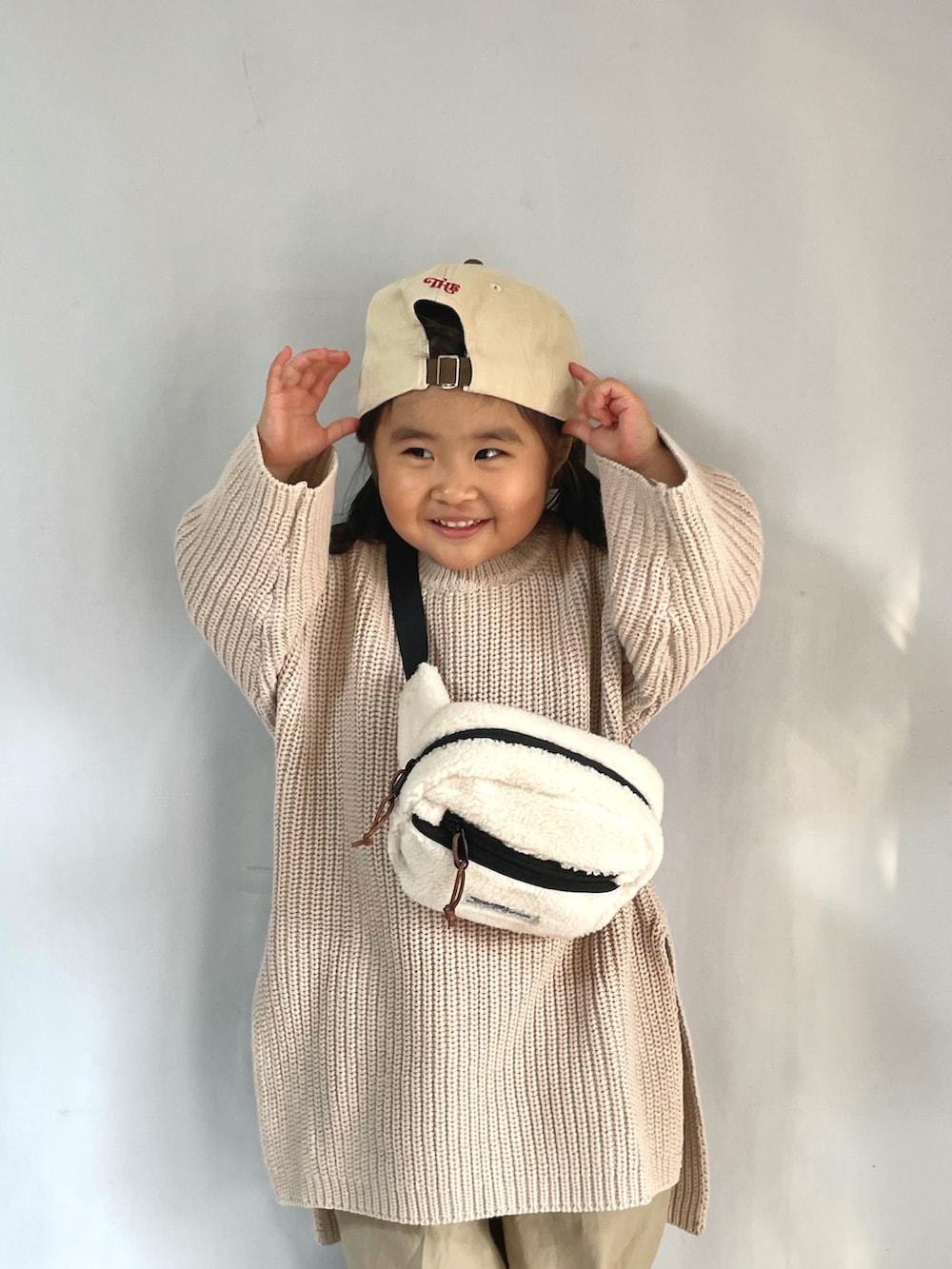 グリーン系のスニーカー、ベージュ系のその他パンツ、ホワイト系のボディバッグ/ウエストポーチを着用したキッズの冬コーディネートの3枚目の写真