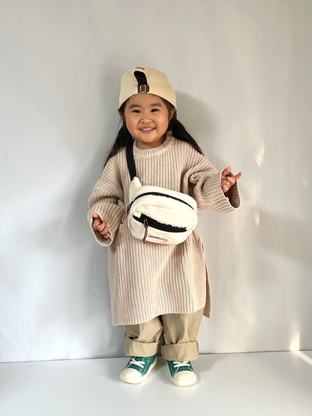 グリーン系のスニーカー、ベージュ系のその他パンツ、ホワイト系のボディバッグ/ウエストポーチを着用したキッズの冬コーディネートの5枚目の写真