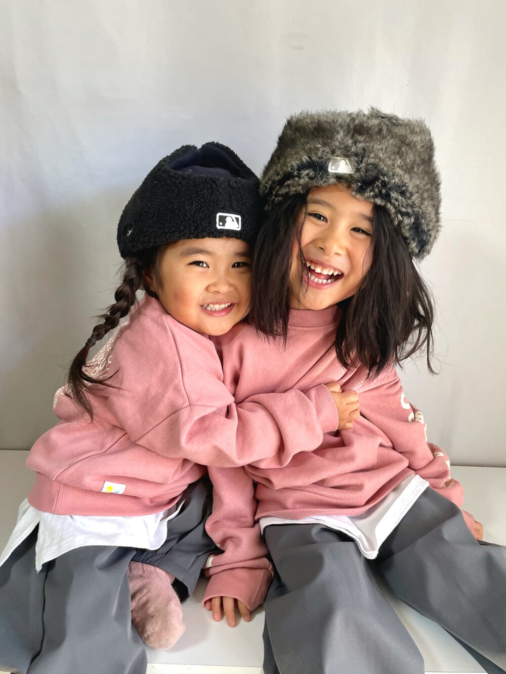 グレー系のスラックス、ピンク系のスウェット、ブラック系のキャップを着用したキッズの冬コーディネートの3枚目の写真