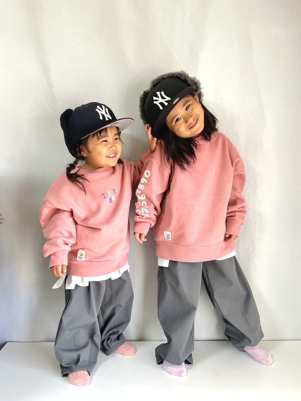 グレー系のスラックス、ピンク系のスウェット、ブラック系のキャップを着用したキッズの冬コーディネートの4枚目の写真