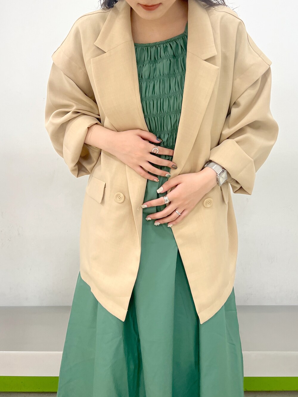 ベージュ系のテーラードジャケット、グリーン系のワンピースを着用したレディースの春コーディネートの4枚目の写真