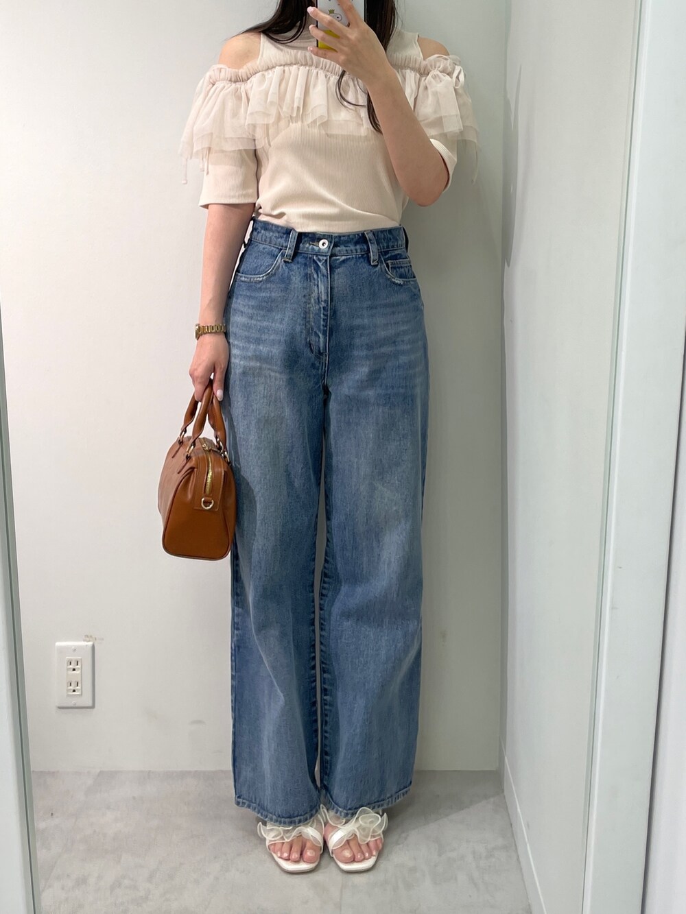 ベージュ系のTシャツ/カットソー、ブルー系のデニムパンツ、ブラウン系のボストンバッグを着用したレディースの春コーディネートの2枚目の写真