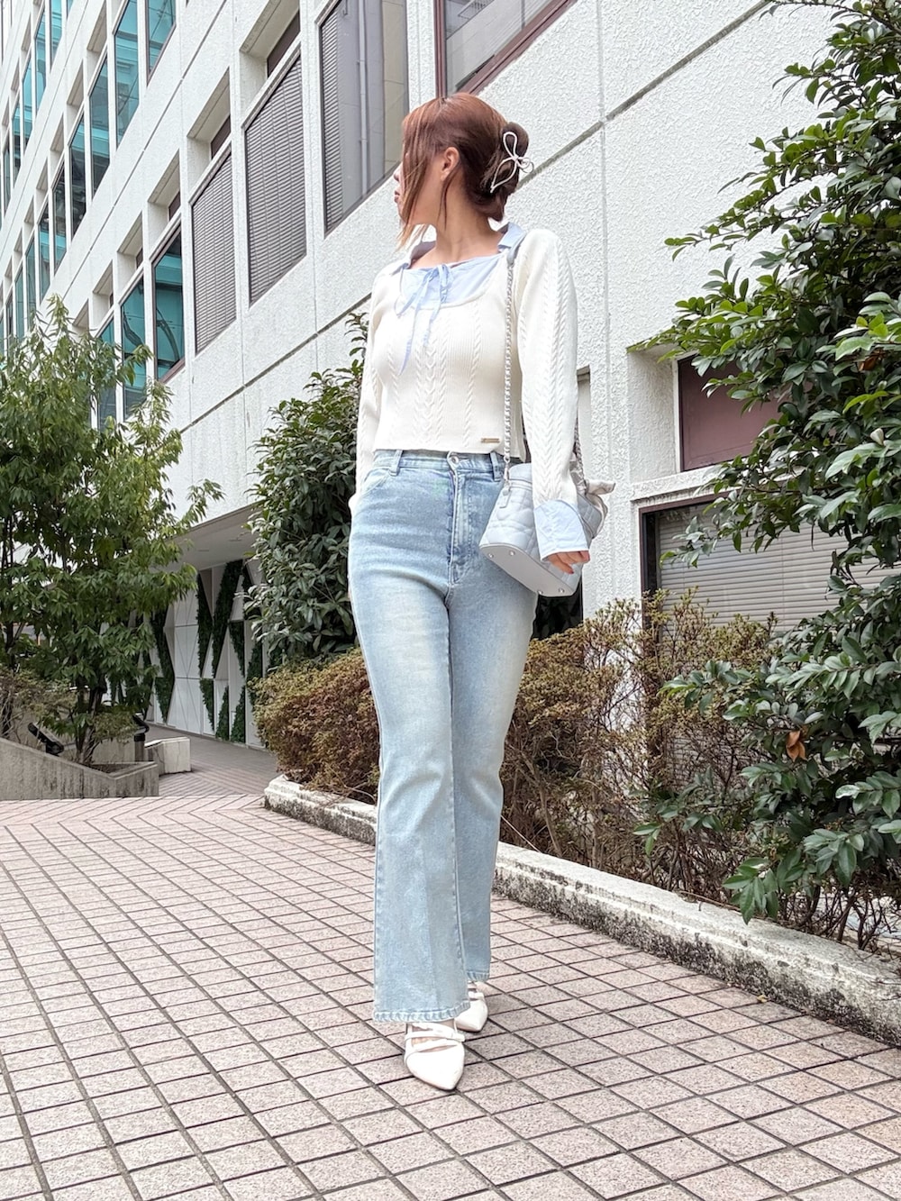 ホワイト系のニット/セーター、ブルー系のショルダーバッグを着用したレディースの冬コーディネートの2枚目の写真