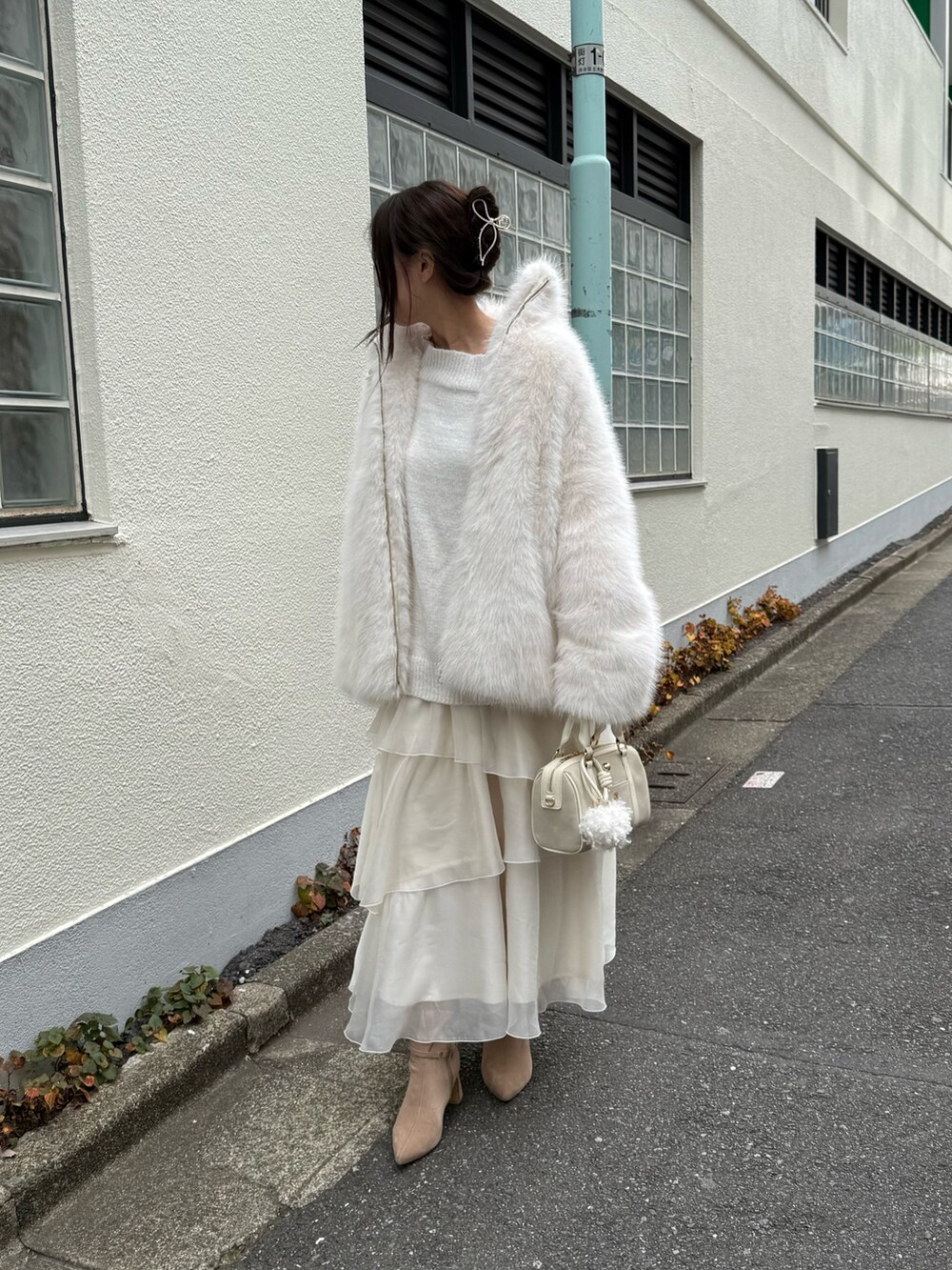 ホワイト系のその他アウター、ホワイト系のボストンバッグ、ベージュ系のブーツを着用したレディースの秋コーディネートの3枚目の写真