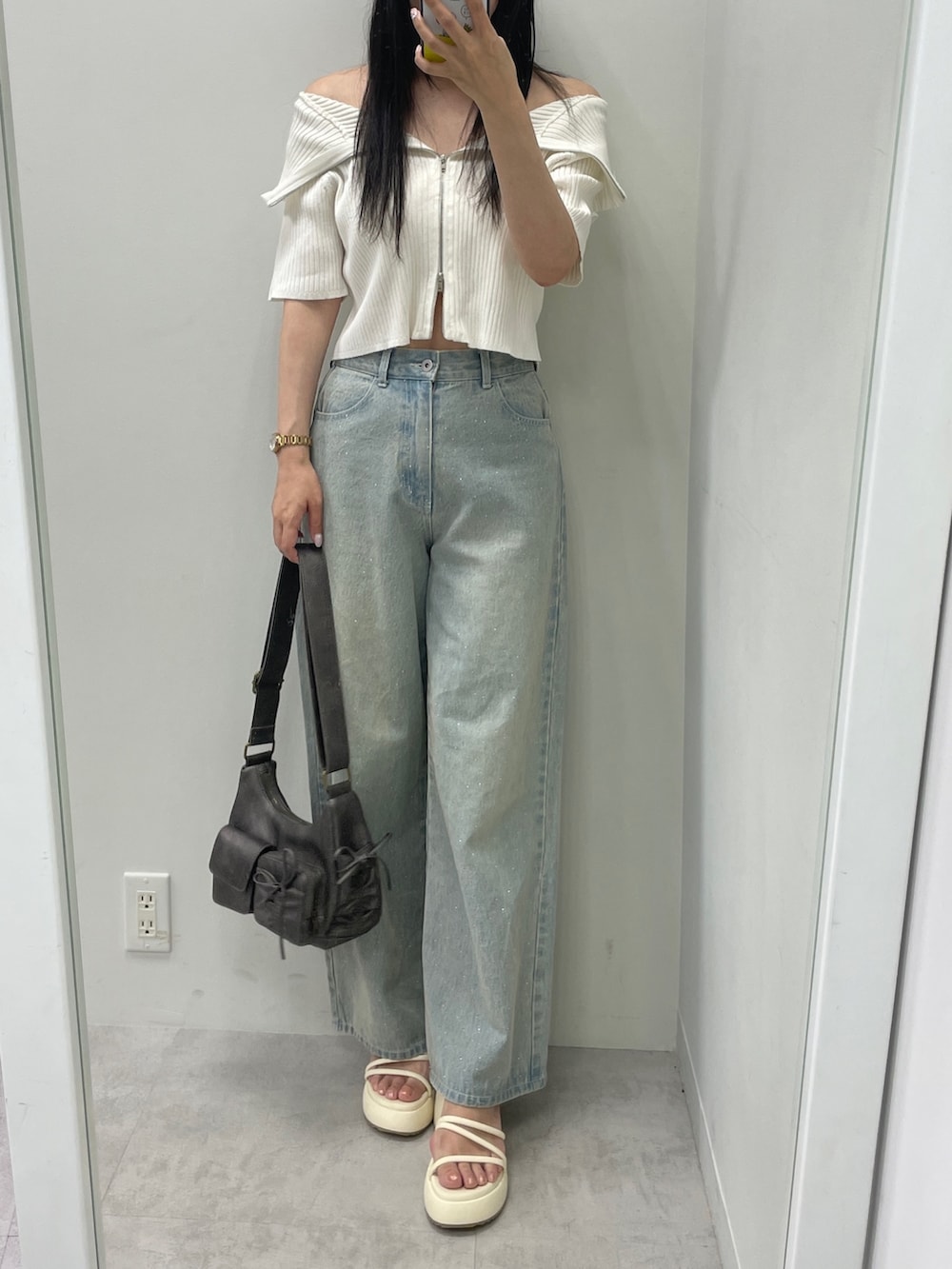 ホワイト系のニット/セーター、ブルー系のデニムパンツ、ブラック系のショルダーバッグを着用したレディースの夏コーディネートの3枚目の写真