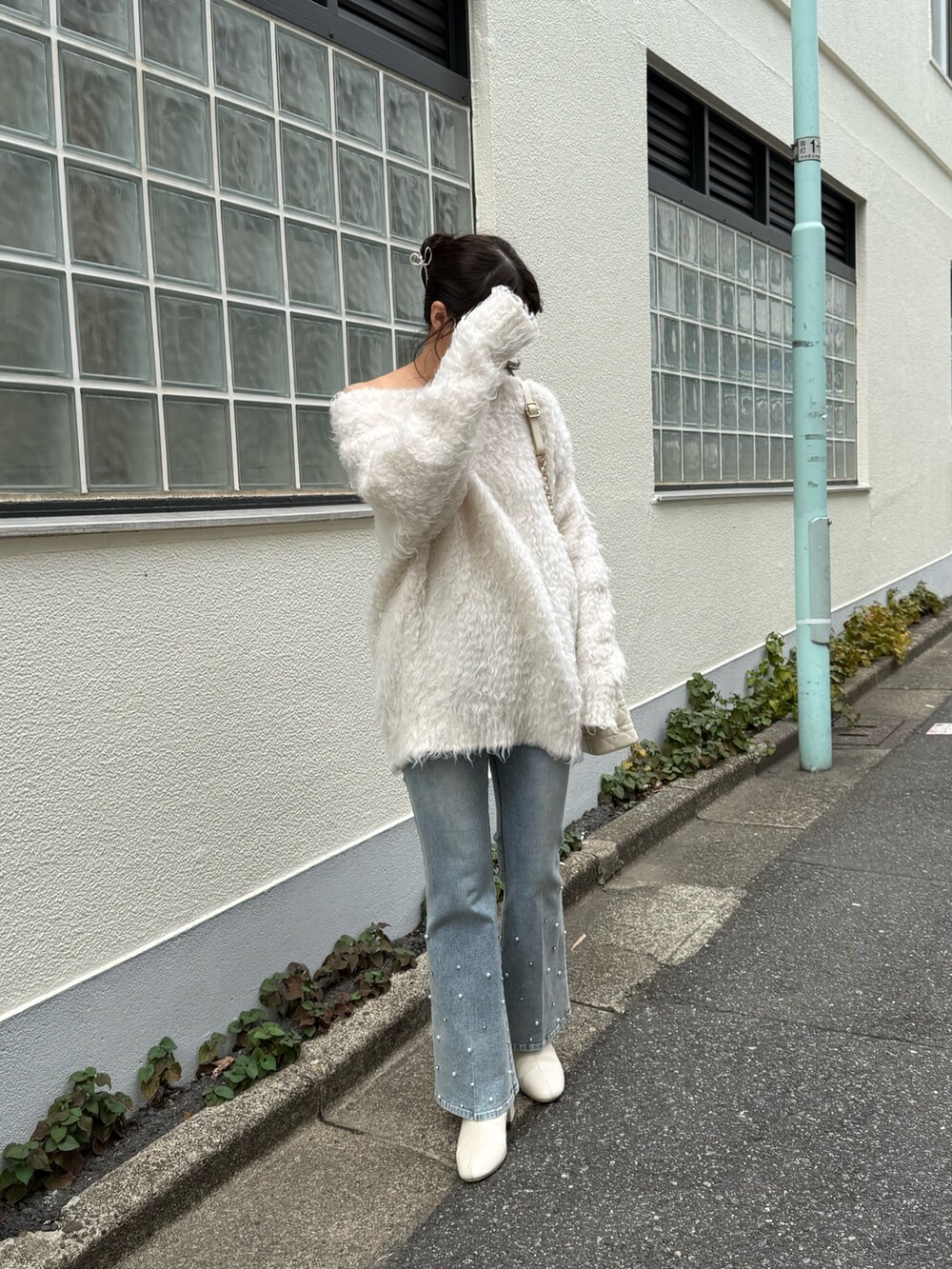 ホワイト系のニット/セーター、ブルー系のデニムパンツ、ホワイト系のショルダーバッグを着用したレディースの秋コーディネートの2枚目の写真