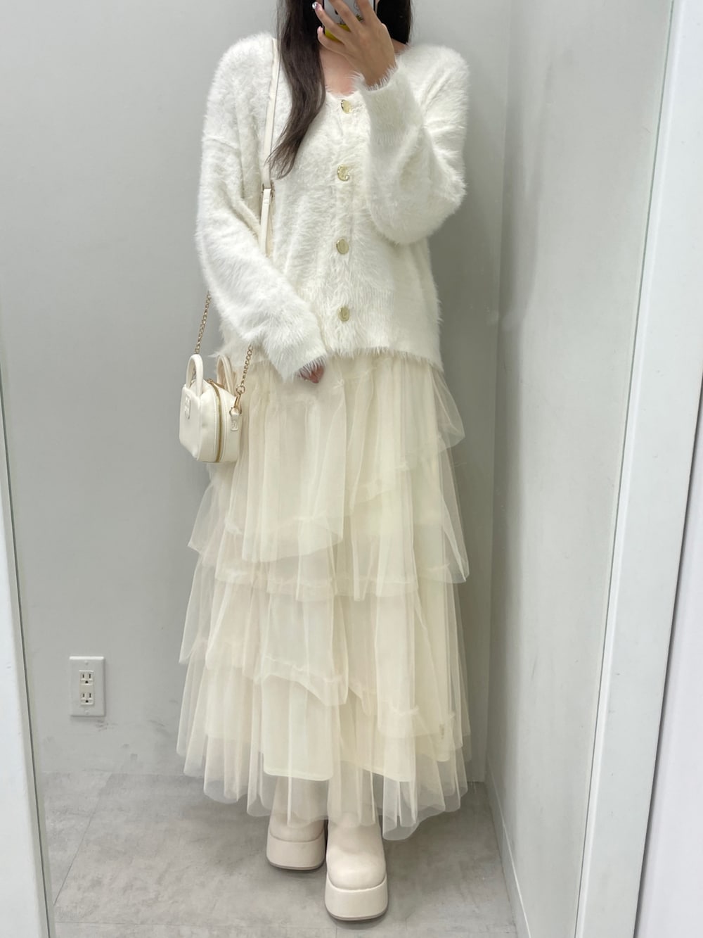 ホワイト系のカーディガン/ボレロ、ホワイト系のスカート、ホワイト系のボストンバッグを着用したレディースの秋コーディネートの2枚目の写真