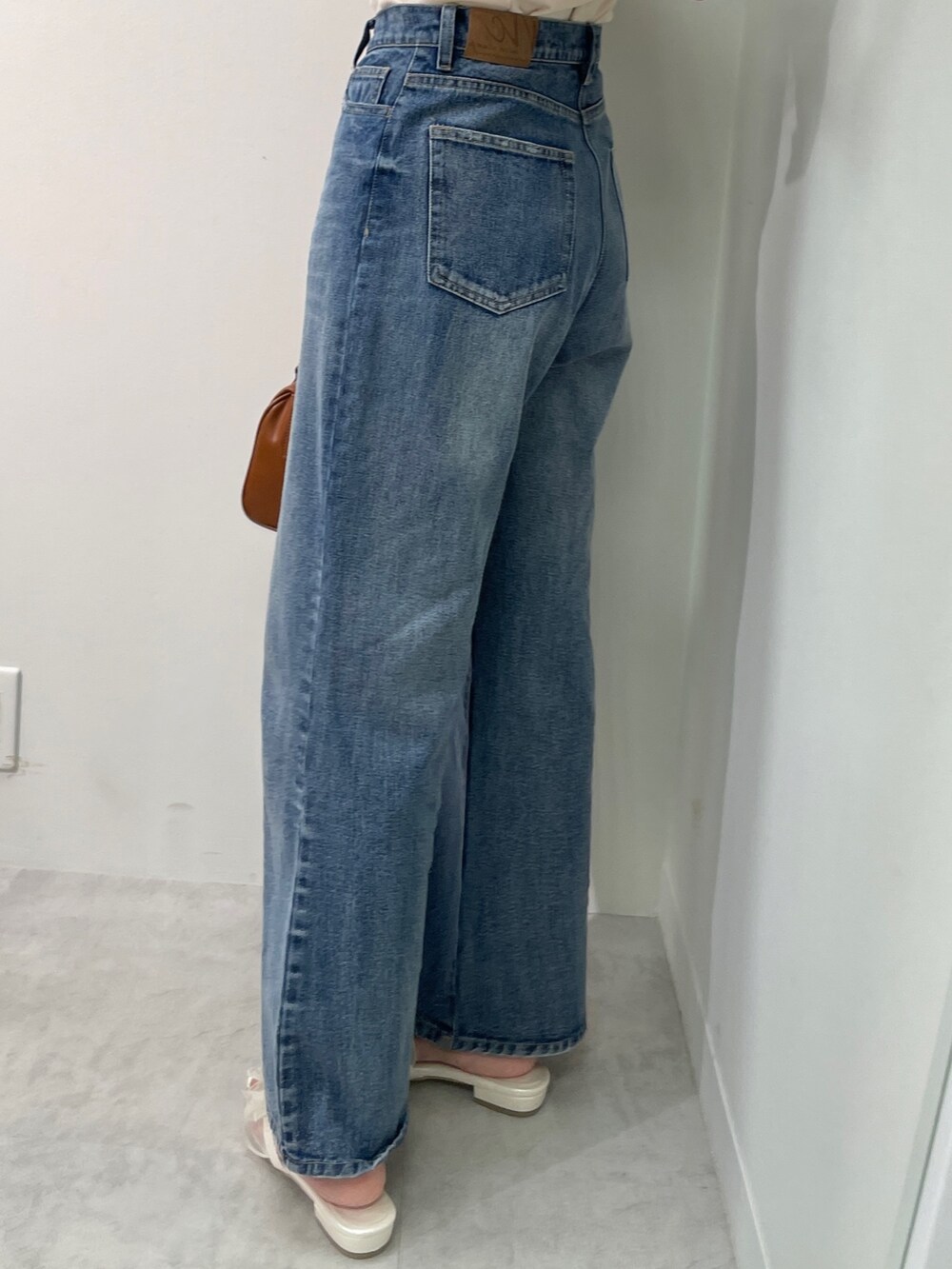 ベージュ系のTシャツ/カットソー、ブルー系のデニムパンツ、ブラウン系のボストンバッグを着用したレディースの春コーディネートの4枚目の写真