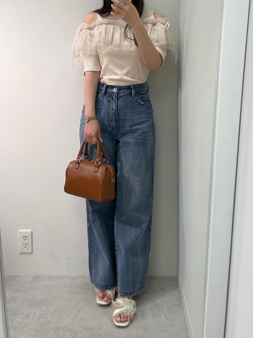 ベージュ系のTシャツ/カットソー、ブルー系のデニムパンツ、ブラウン系のボストンバッグを着用したレディースの春コーディネートの3枚目の写真