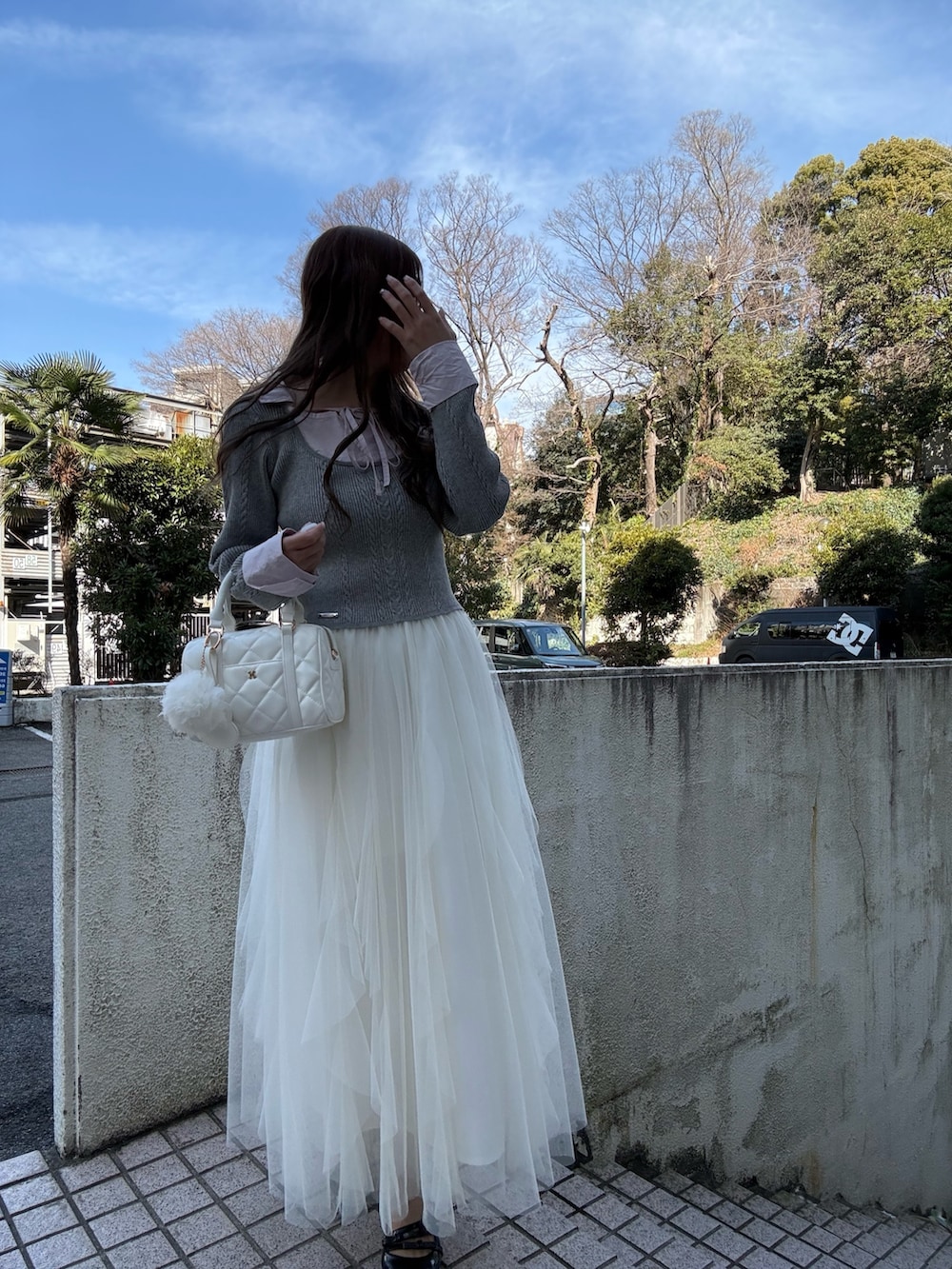 グレー系のニット/セーター、ホワイト系のスカート、ホワイト系のボストンバッグを着用したレディースの冬コーディネートの2枚目の写真