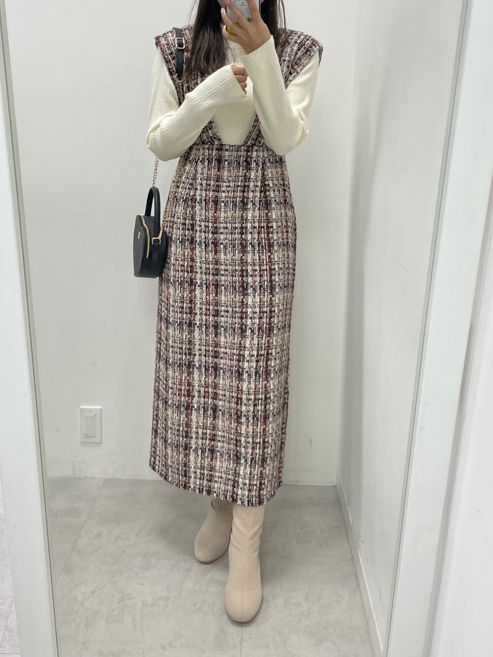 レッド系のジャンパースカート、ホワイト系のニット/セーター、ブラック系のショルダーバッグを着用したレディースの秋コーディネートの2枚目の写真