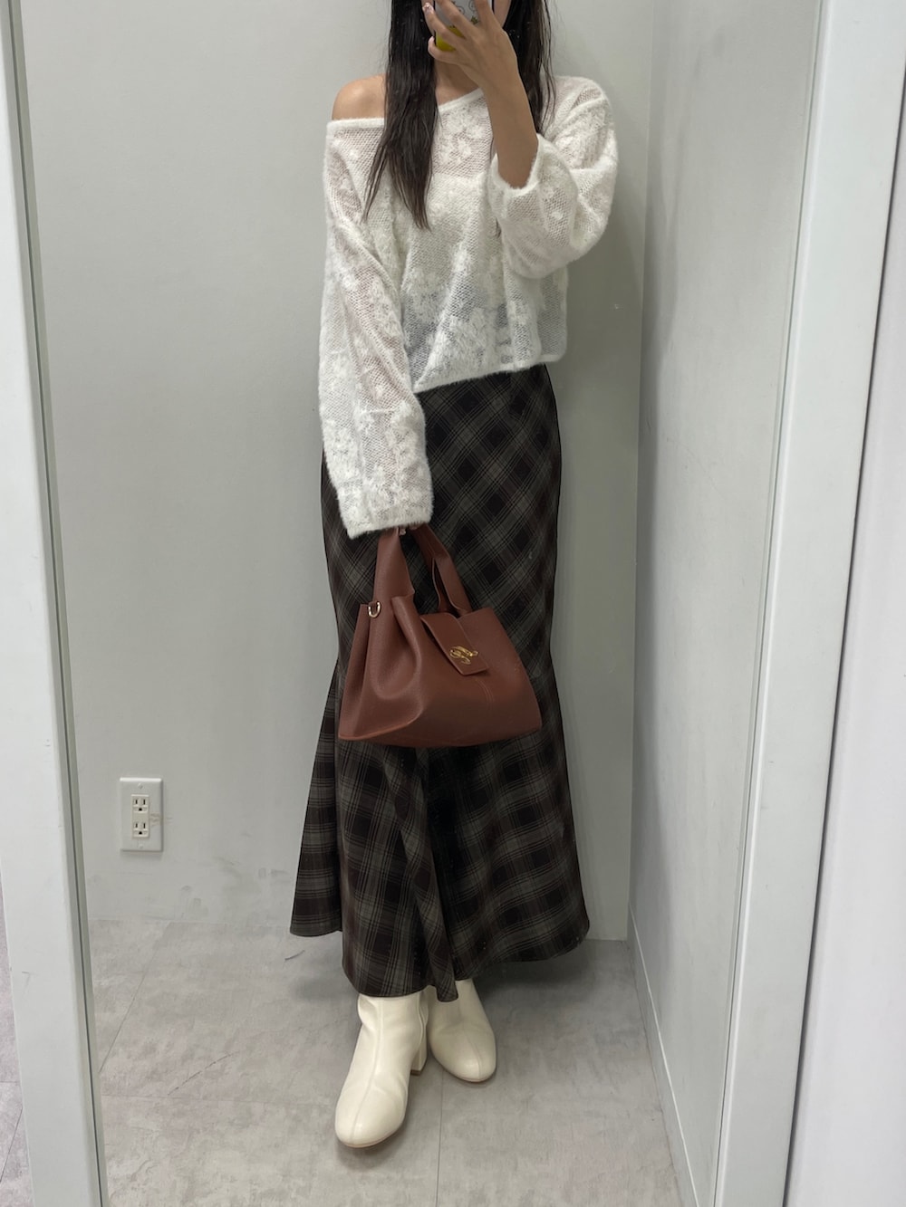 ホワイト系のニット/セーター、ブラウン系のスカート、ブラウン系のハンドバッグを着用したレディースの秋コーディネートの2枚目の写真
