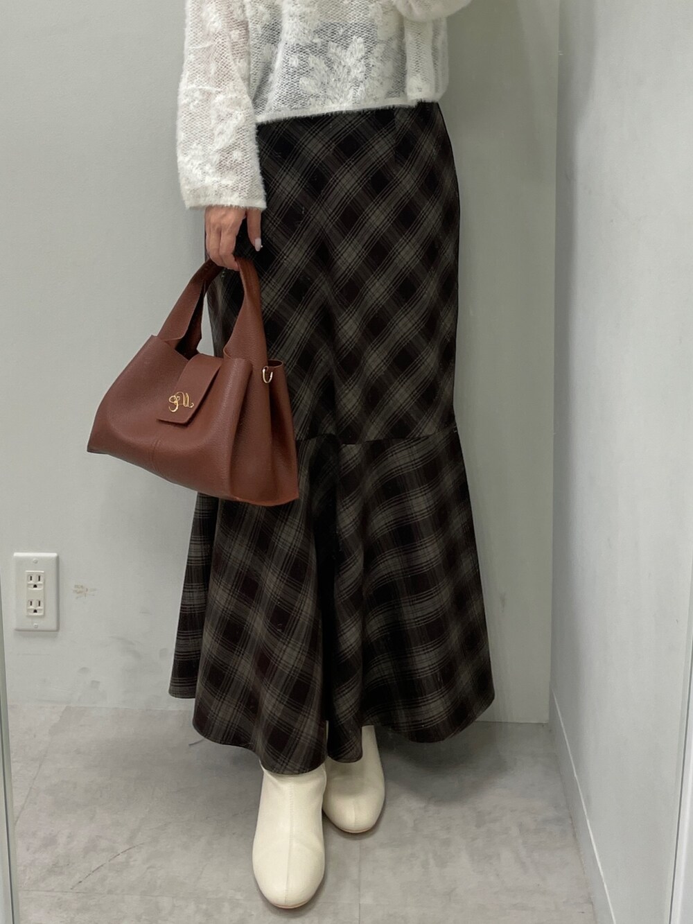 ホワイト系のニット/セーター、ブラウン系のスカート、ブラウン系のハンドバッグを着用したレディースの秋コーディネートの8枚目の写真