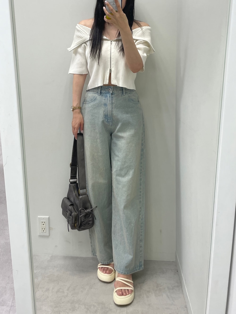 ホワイト系のニット/セーター、ブルー系のデニムパンツ、ブラック系のショルダーバッグを着用したレディースの夏コーディネートの2枚目の写真