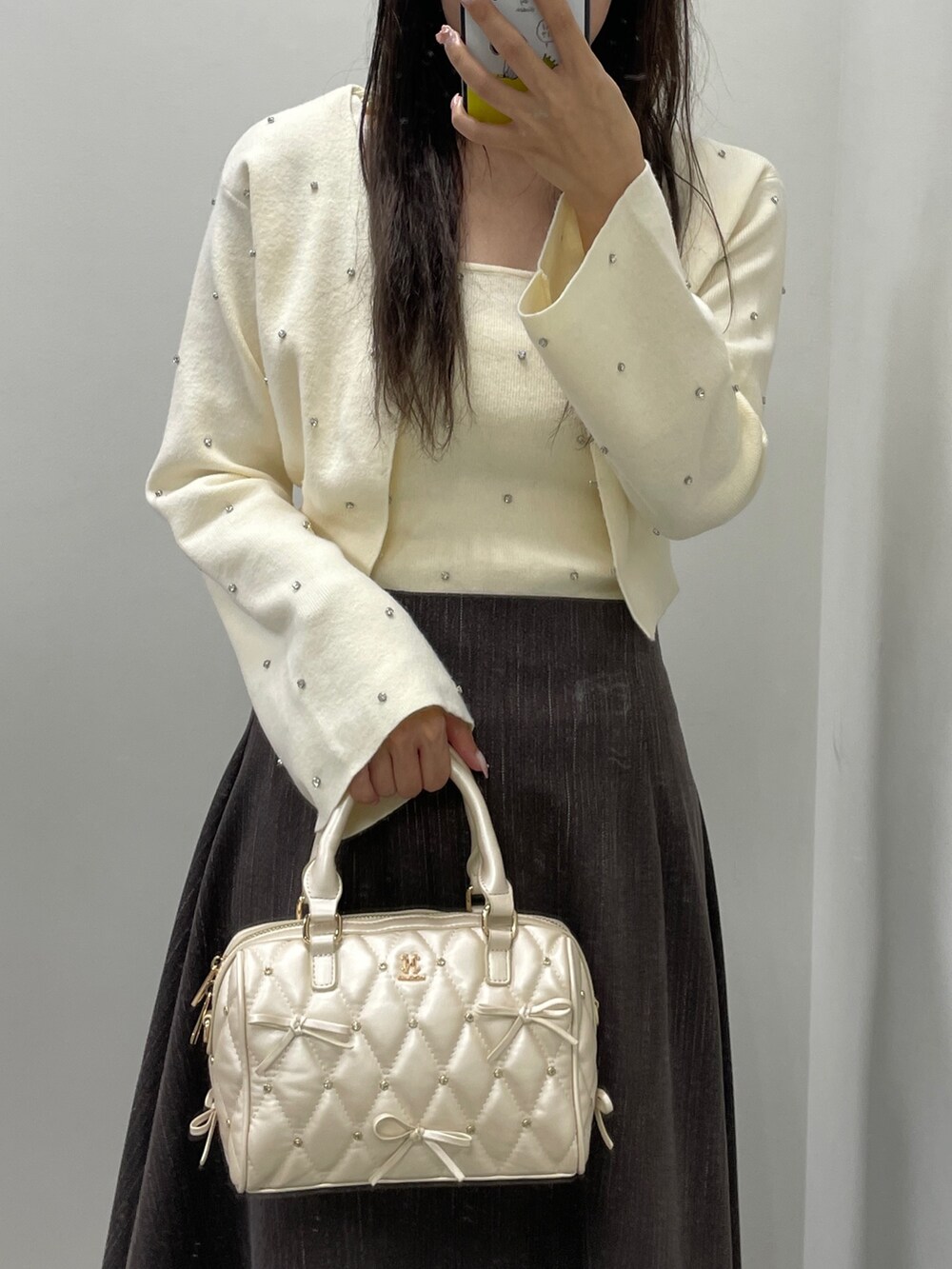 ホワイト系のカーディガン/ボレロ、ホワイト系のキャミソール、ブラウン系のスカートを着用したレディースの秋コーディネートの4枚目の写真