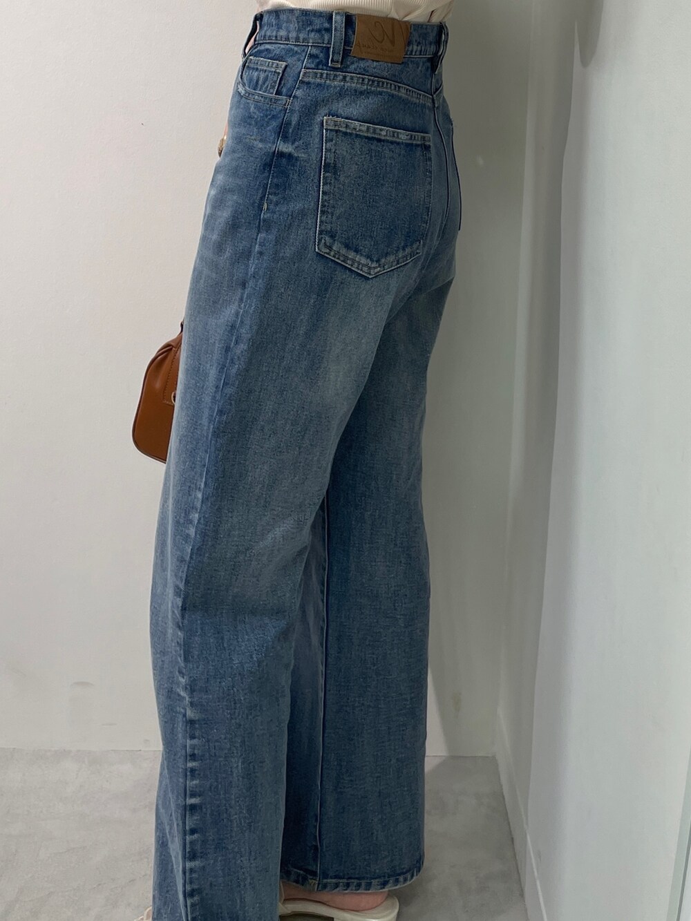 ベージュ系のTシャツ/カットソー、ブルー系のデニムパンツ、ブラウン系のボストンバッグを着用したレディースの春コーディネートの5枚目の写真