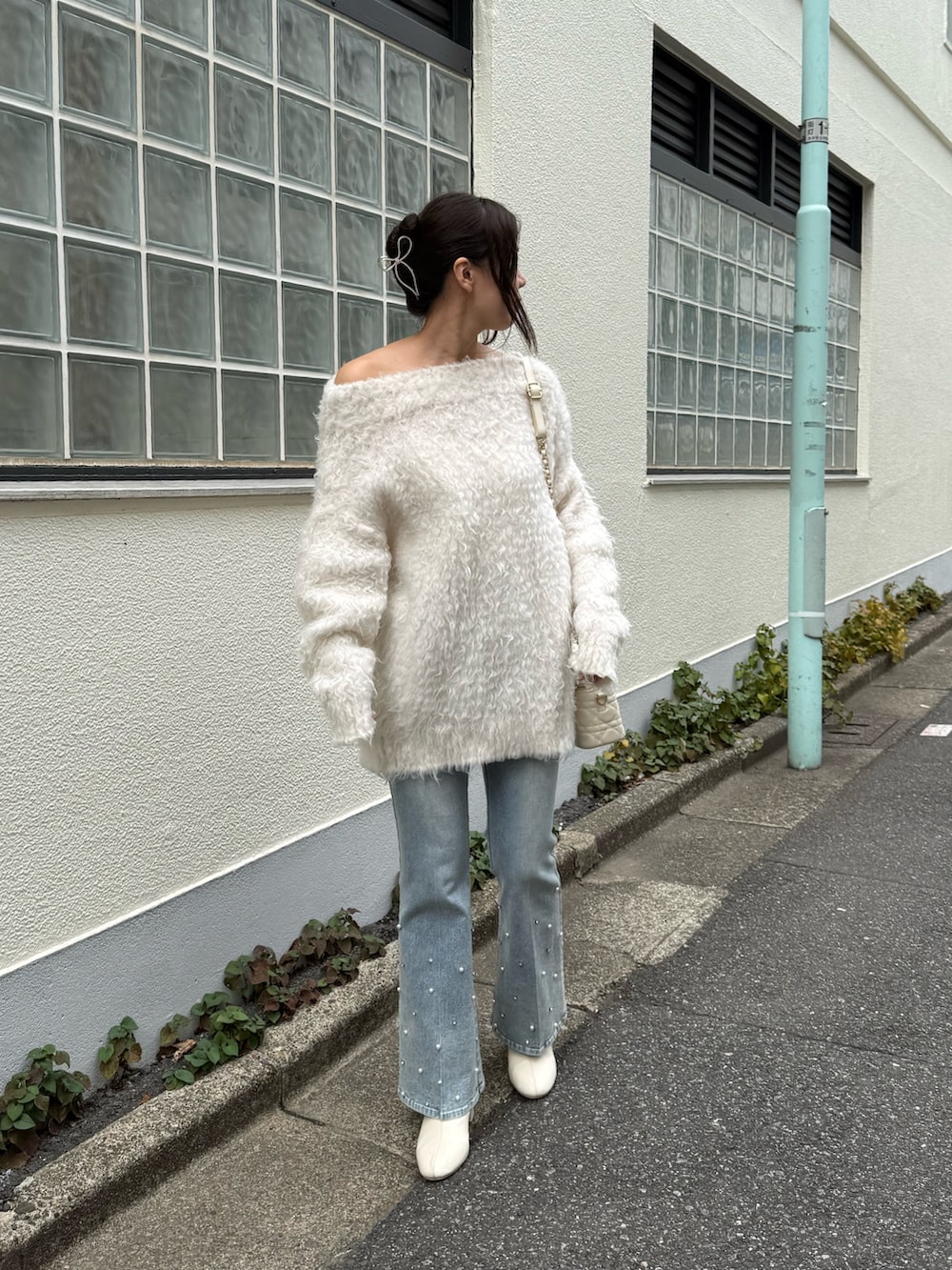 ホワイト系のニット/セーター、ブルー系のデニムパンツ、ホワイト系のショルダーバッグを着用したレディースの秋コーディネートの3枚目の写真