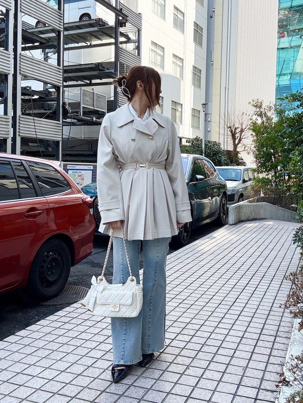 ホワイト系のトレンチコート、ブルー系のデニムパンツ、ホワイト系のショルダーバッグを着用したレディースの冬コーディネートの2枚目の写真