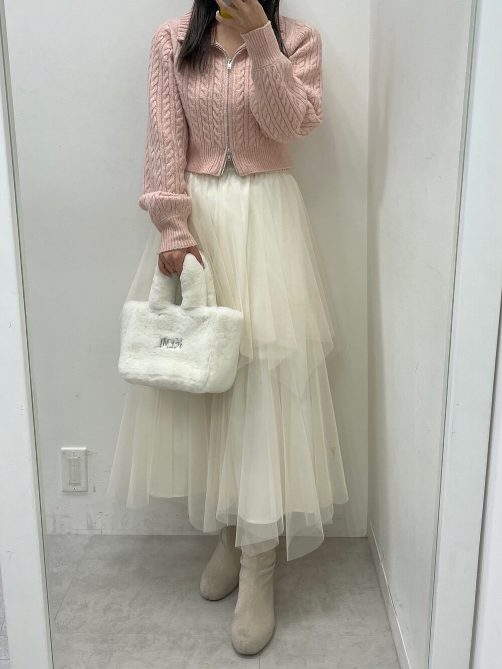 ピンク系のニット/セーター、ホワイト系のスカート、ホワイト系のトートバッグを着用したレディースの冬コーディネートの2枚目の写真