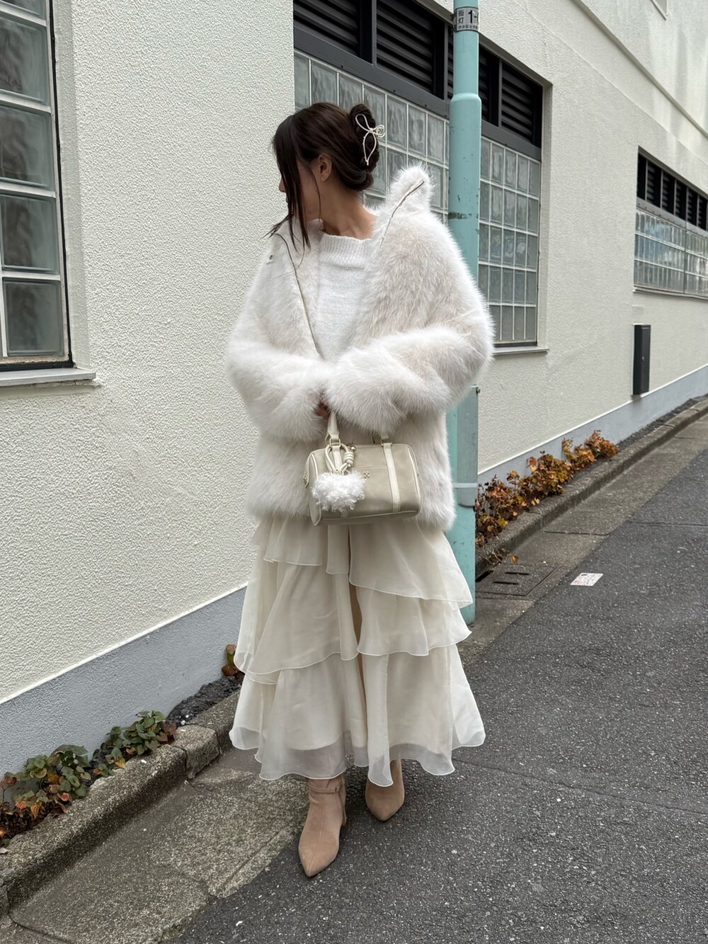 ホワイト系のその他アウター、ホワイト系のボストンバッグ、ベージュ系のブーツを着用したレディースの秋コーディネートの2枚目の写真