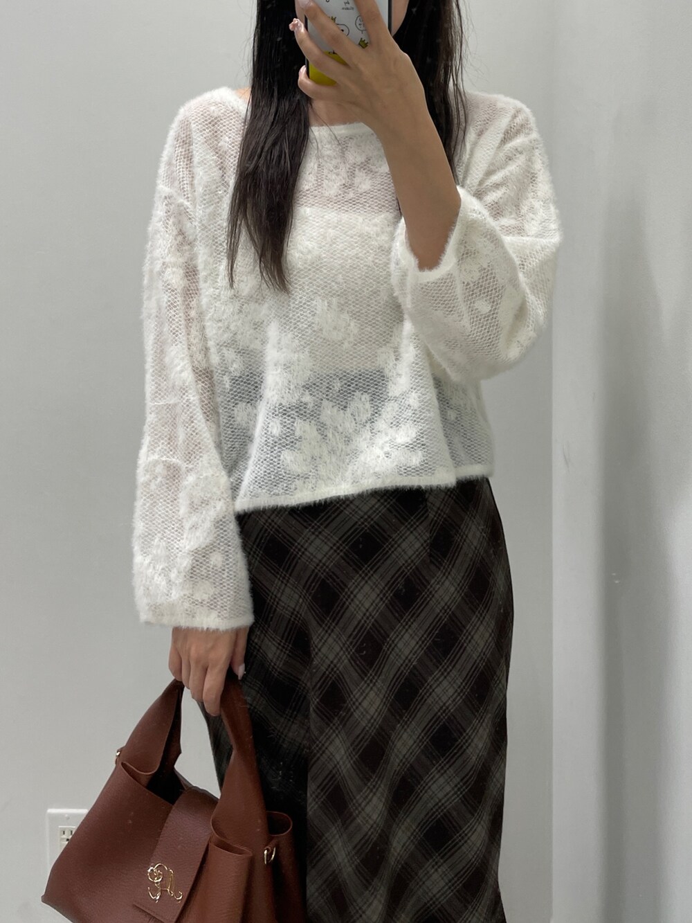 ホワイト系のニット/セーター、ブラウン系のスカート、ブラウン系のハンドバッグを着用したレディースの秋コーディネートの6枚目の写真