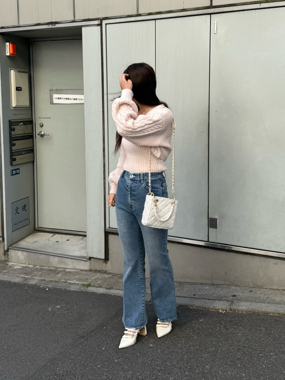 ピンク系のアンサンブル、ブルー系のデニムパンツ、ホワイト系のショルダーバッグを着用したレディースの冬コーディネートの2枚目の写真