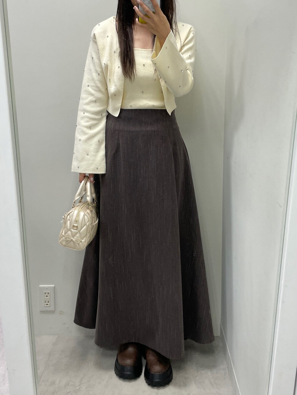 ホワイト系のカーディガン/ボレロ、ホワイト系のキャミソール、ブラウン系のスカートを着用したレディースの秋コーディネートの2枚目の写真