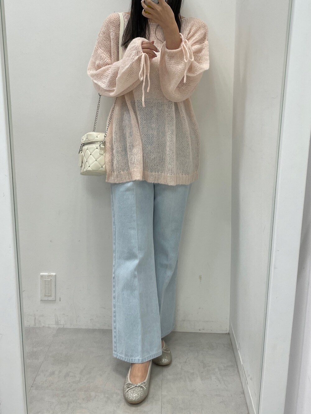 ピンク系のニット/セーター、ブルー系のデニムパンツ、ブラック系のショルダーバッグを着用したレディースの冬コーディネートの2枚目の写真