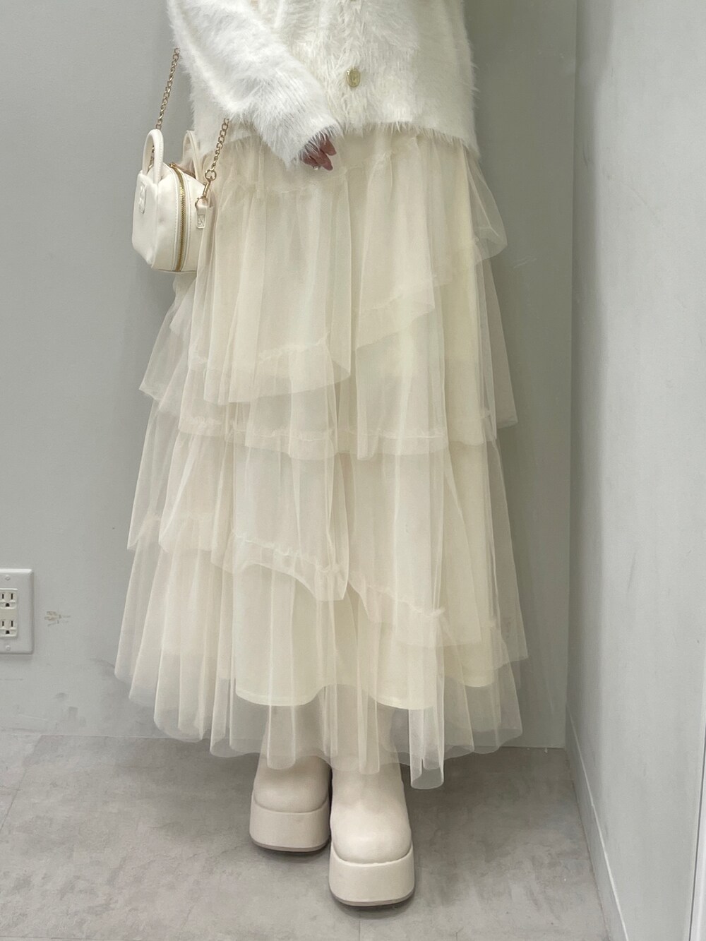 ホワイト系のカーディガン/ボレロ、ホワイト系のスカート、ホワイト系のボストンバッグを着用したレディースの秋コーディネートの6枚目の写真