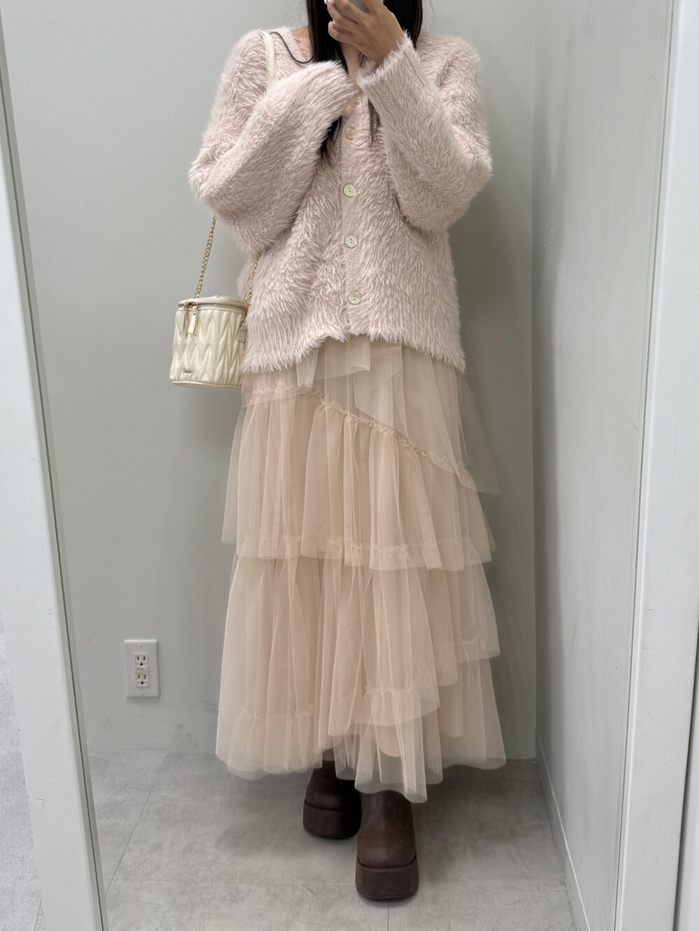 ピンク系のカーディガン/ボレロ、ホワイト系のショルダーバッグ、ブラウン系のブーツを着用したレディースの秋コーディネートの2枚目の写真