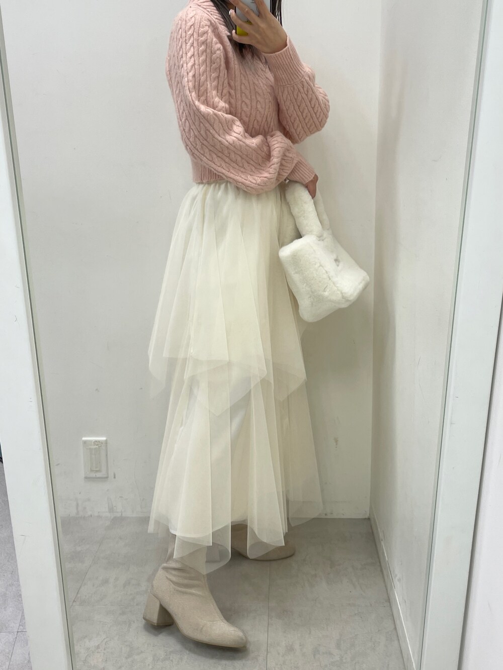 ピンク系のニット/セーター、ホワイト系のスカート、ホワイト系のトートバッグを着用したレディースの冬コーディネートの3枚目の写真