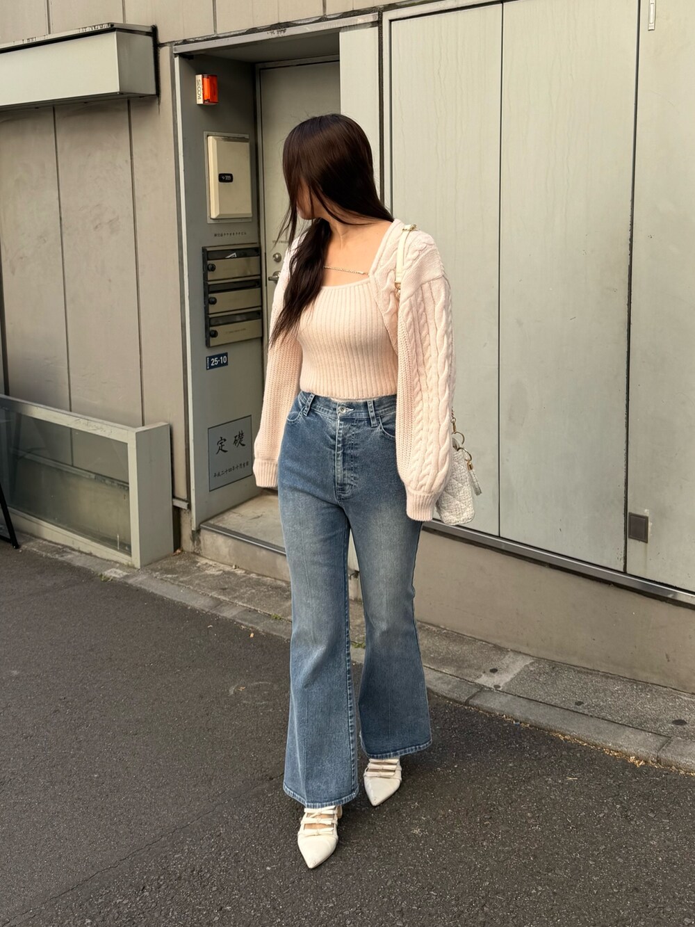 ピンク系のアンサンブル、ブルー系のデニムパンツ、ホワイト系のショルダーバッグを着用したレディースの冬コーディネートの3枚目の写真